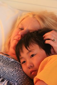 A young boy cuddles with his adopted mother.